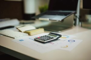 Calculator on a table next to a laptop for tax planning